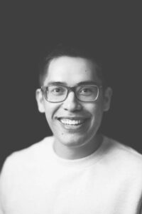 Jacob Campbell headshot in black and white wearing glasses and smiling in a white t-shirt