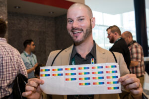 ACPA member holding up a sticker sheet of rainbow stickers and smiling at the camera