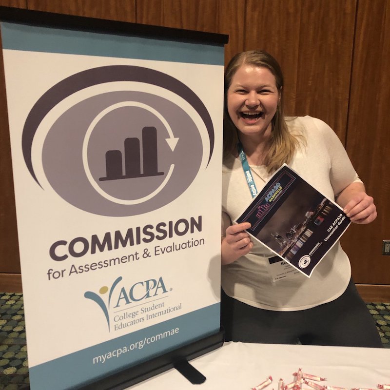 Commission smiling face Commission for Assessment & Evaluation smiling member holding a flyer