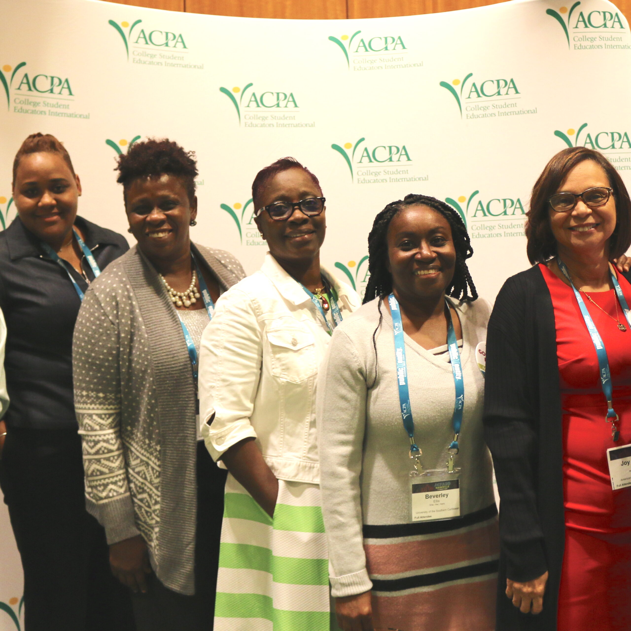 5 Caribbean Tertiary International Division members posing for a photo in front of the ACPA logo