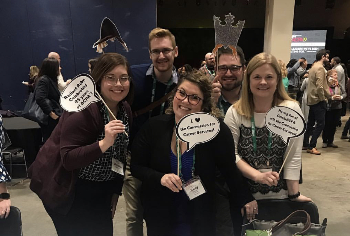 5 Commission for Career Services leaders holding photo booth signs and smiling for a photo