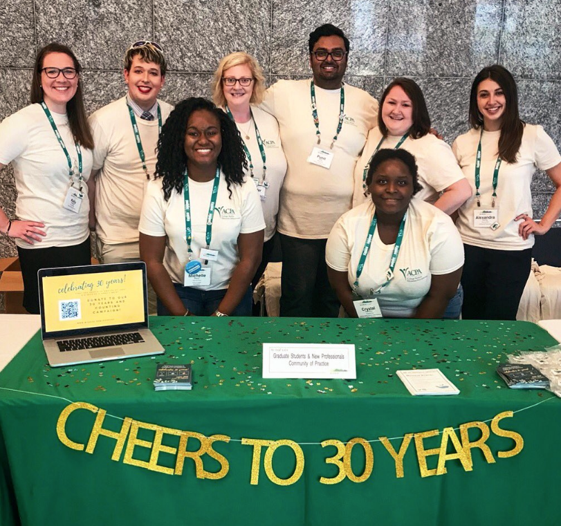 Graduate Students and New Professionals Community of Practice standing behind a table that reads CHEERS TO 30 YEARS and smiling for a photo