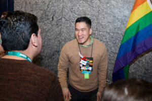 CSGI leader smiling at a new member with a rainbow flag to the right