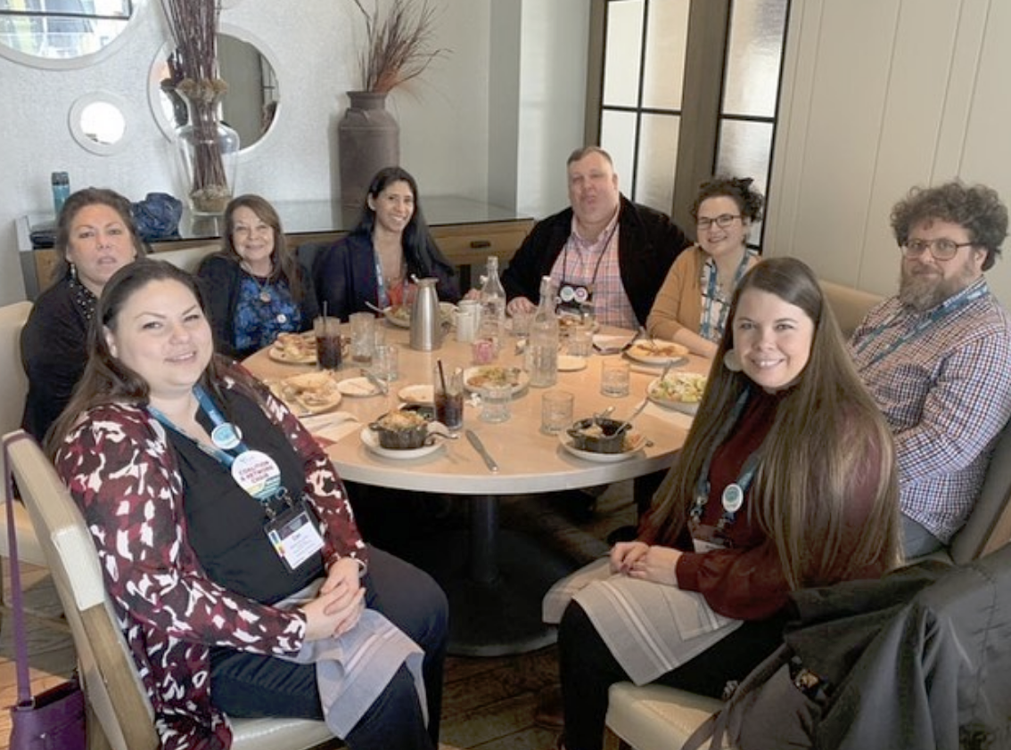 a group of ISAN members sitting around a dinner table smiling at the camera