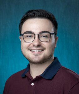 A headshot of Tanner Gill. A smiling White man with brown hair dressed in a polo.