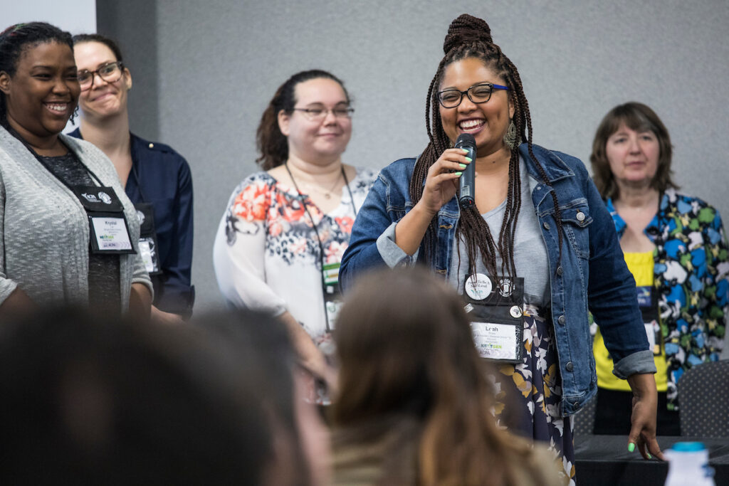 student at the nextgen institute holding a microphone surrounded by other participants with smiling faces