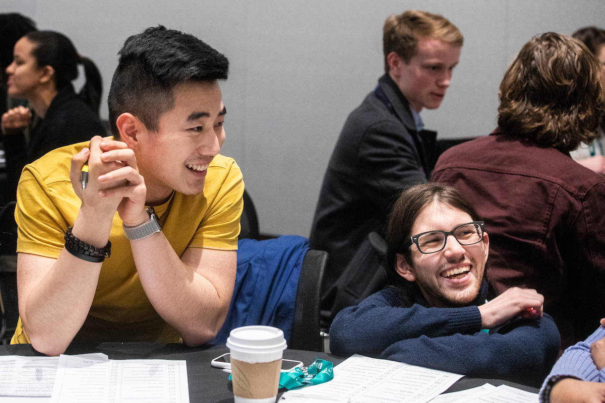 two students at the NextGen Institute smiling while sitting around a table