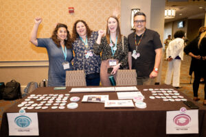 group of ISAN and NAIC members smiling and cheering toward the camera at their table during CelebrACPA