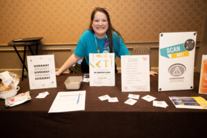 ACPA member from the Commission for Emergency Preparedness smiles at the camera while behind the swag table during CelebrACPA