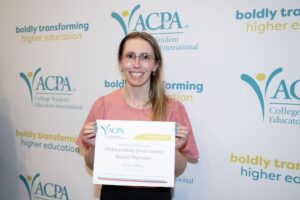 photo of ACPA member holding an ACPA award and smiling at the camera